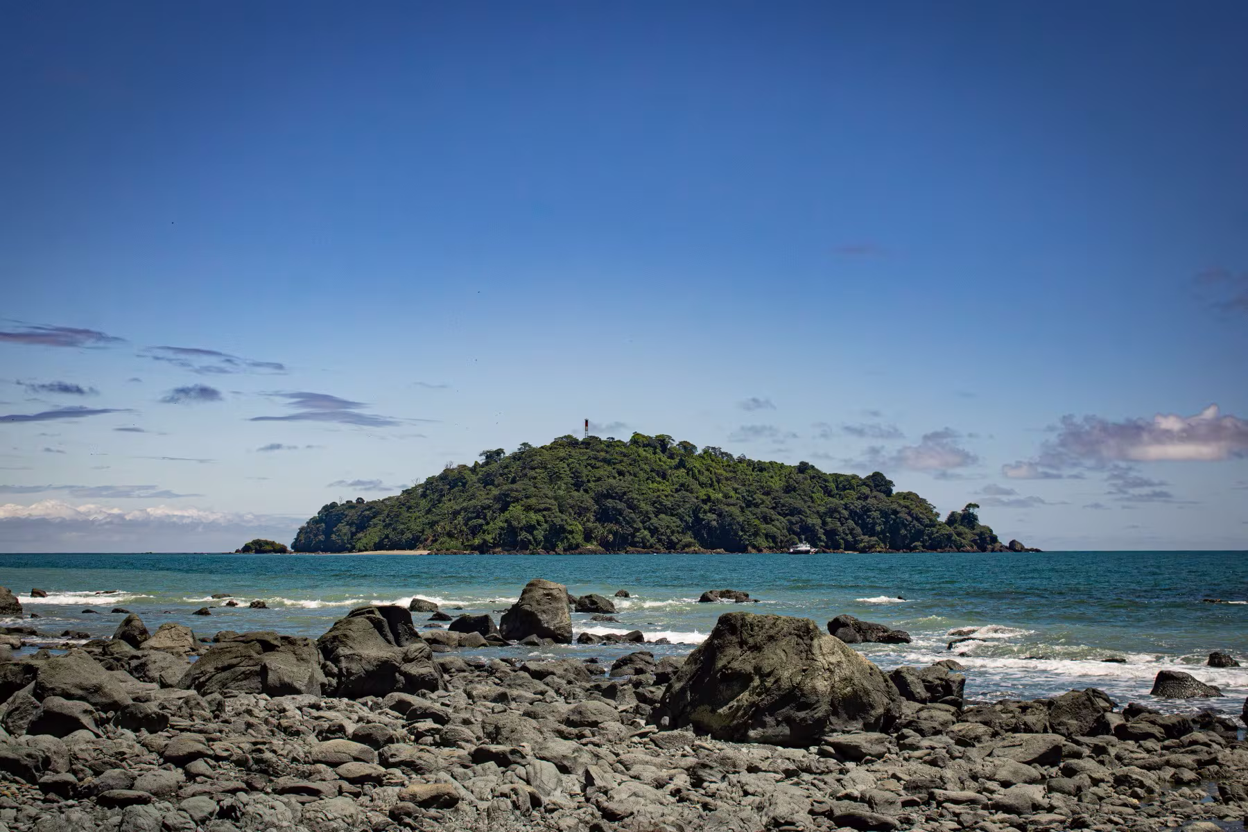 La isla Gorgonilla vista desde la costa rocosa de Gorgona, bajo un cielo azul